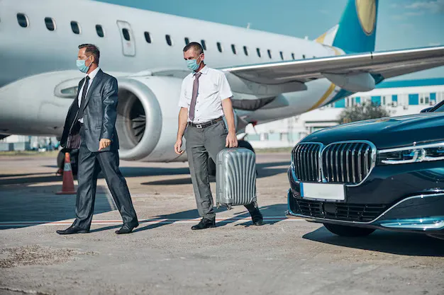 How a Chauffeur Service from JFK Airport Helps You Overcome Travel Stress 1 Luxury chauffeur service from JFK Airport – professional driver assisting business traveler with luggage near private car.